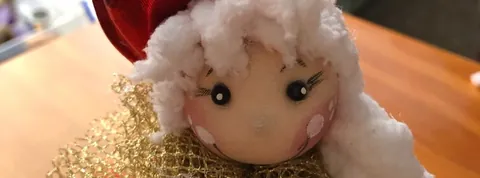 Cara de ángel con gorro rojo, pelo blanco y malla dorada